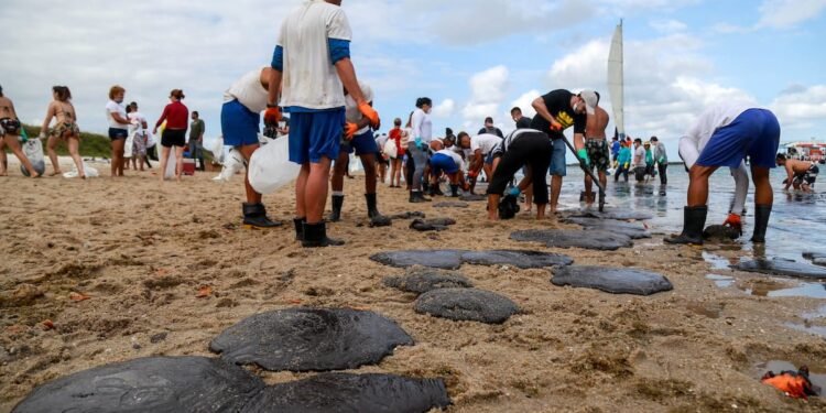 People work to remove an oil spill on Suape beach in Cabo de Santo Agostinho