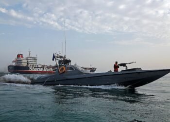 A boat of the Iranian Revolutionary Guard sails next to Stena Impero at Bandar Abbas port