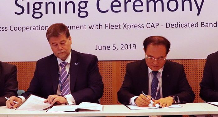 Two men in suits sign documents