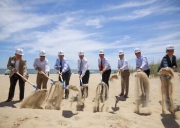 Men on beach shoveling sand