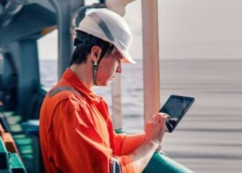 Marine chief officer or captain on deck of vessel or ship watching digital tablet. Internet and home connection at sea.