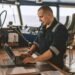 Marine navigational officer or technician is using laptop or notebook at sea. Job at sea