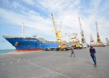 FILE PHOTO - People walk past a ship docked at the Red Sea port of Hodeidah