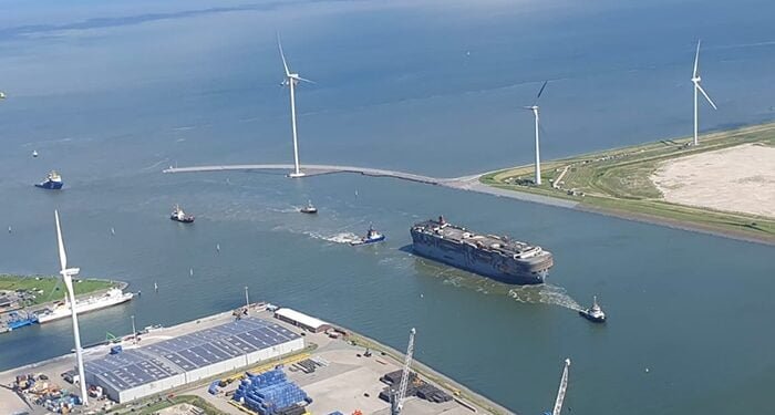 Burned out car carrier towed into port