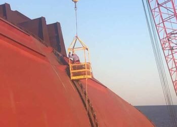 Technicians on side of ship in basket