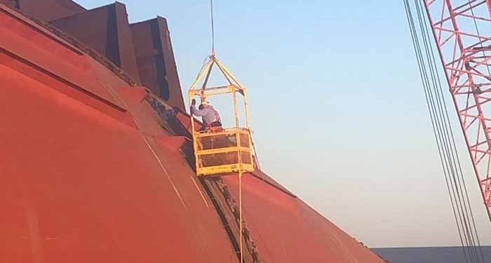 Technicians on side of ship in basket